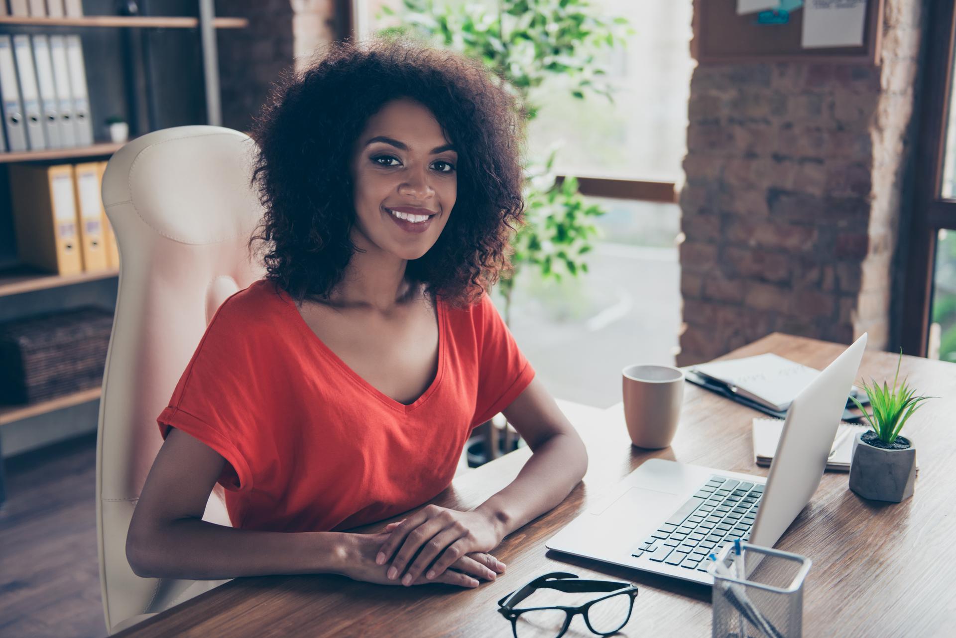 Portrait of trendy charming attorney with beaming smile in casual outfit sitting at desk in modern office looking at camera. People person profession vector concept